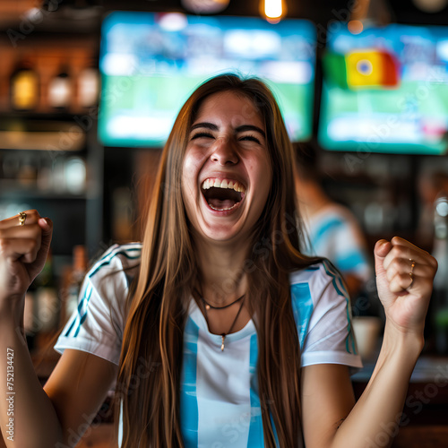 cheering for favorite team of Argentina and celebrating victory, Happy young girl emotionally gesturing while watching football match in sports bar