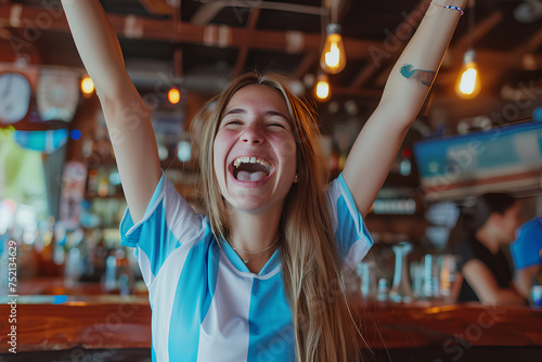 cheering for favorite team of Argentina and celebrating victory, Happy young girl emotionally gesturing while watching football match in sports bar