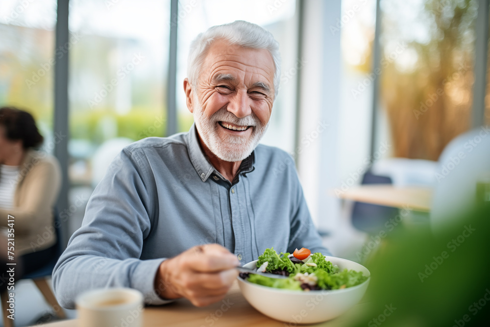 An elderly man in a retirement facility joyfully indulges in a nutritious lunch, reflecting a lifestyle of health and satisfaction An elderly man in a retirement facility joyfully indulges in a nutritious lunch, reflecting a lifestyle of health and satisfaction