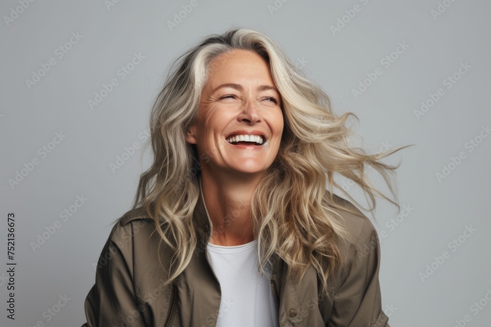 Portrait of a happy mature woman laughing and looking up over grey background Portrait of a happy mature woman laughing and looking up over grey background