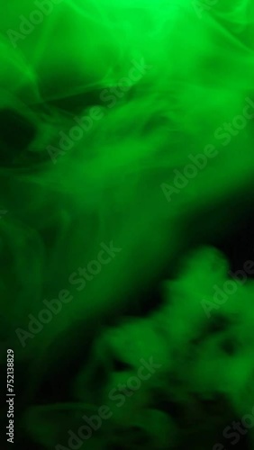 vertical footage of green smoke dark background
