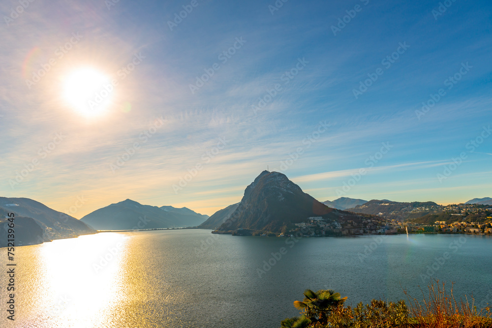 Sunlight on Lake Lugano and City with Mountain and Blue Sky in Lugano, Ticino in Switzerland.