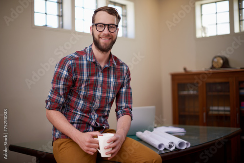 Portrait, laptop and architect in office with smile for career in construction industry and coffee. Man, contractor and entrepreneur of startup, small business and blueprint with floor plan on desk photo