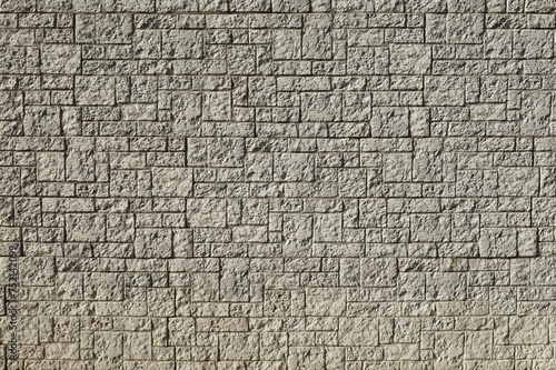 Large concrete wall made of different shaped tiles imitating rough stone. Background and texture