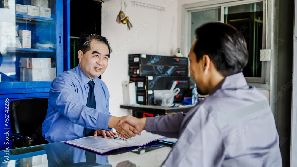 Asian mechanic repairman pass job interview sit in front of Business man answers questions shake hands finish successfully formal meeting at car repair shop, recruitment agency concept