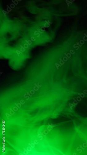 vertical footage of green smoke dark background
