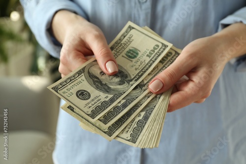 Money exchange. Woman counting dollar banknotes on blurred background, closeup