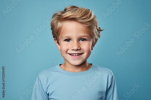 Portrait of a cute little boy with blond hair on blue background