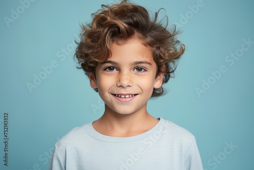 Portrait of a smiling little boy with curly hair on a blue background