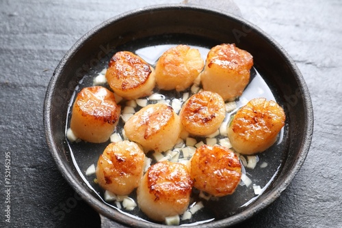 Delicious fried scallops in dish on dark gray textured table, above view