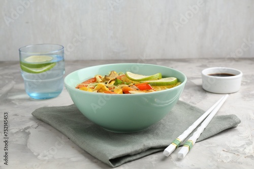 Stir-fry. Delicious cooked noodles with chicken and vegetables in bowl served on gray textured table