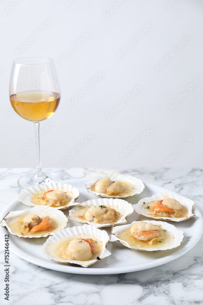 Fried scallops in shells and wine on white marble table
