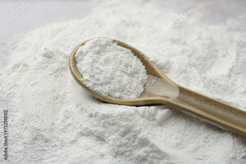 Pile of baking powder and spoon on table, closeup