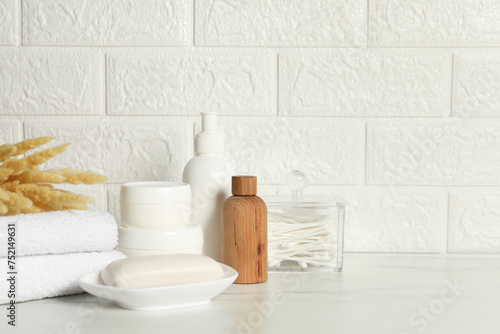 Fototapeta Naklejka Na Ścianę i Meble -  Different bath accessories, personal care products and spikelets on white table near brick wall, space for text