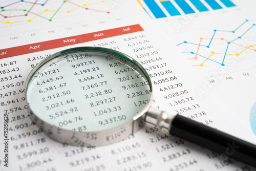 Magnifying glass on spreadsheet and graph paper. Financial development  Banking Account  Statistic  Investment Analytic research data economy  Business.