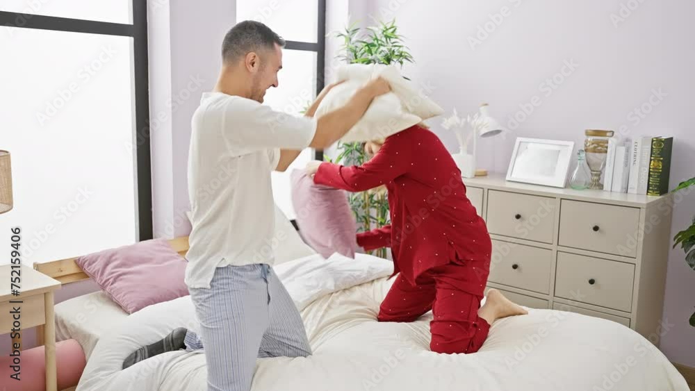 A man and woman playfully having a pillow fight in a cozy, bright bedroom, portraying a happy couple enjoying their loving relationship indoors. A man and woman playfully having a pillow fight in a cozy, bright bedroom, portraying a happy couple enjoying their loving relationship indoors.