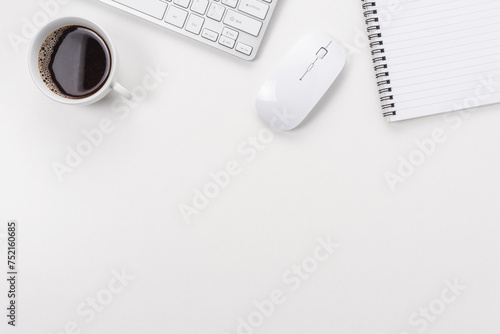 Workspace with computer keyboard, office supplies, and coffee cup on white background. Top view with copy space.