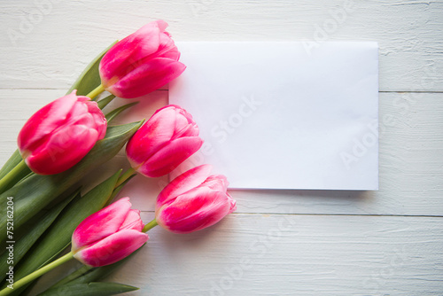 Fototapeta Naklejka Na Ścianę i Meble -  Pink tulips and white mockup blank on wooden background. Flat lay, top view, copy space. Women's Day or Mother's Day greeting card