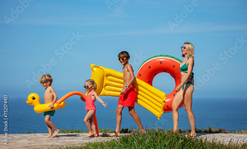 Family carries floats on sunny seaside walk vacations concept
