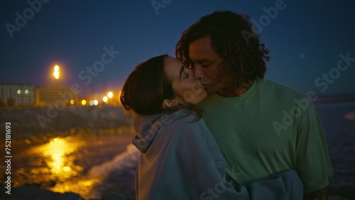 Tender youngsters enjoy night ocean beach closeup. Gentle man kissing girlfriend