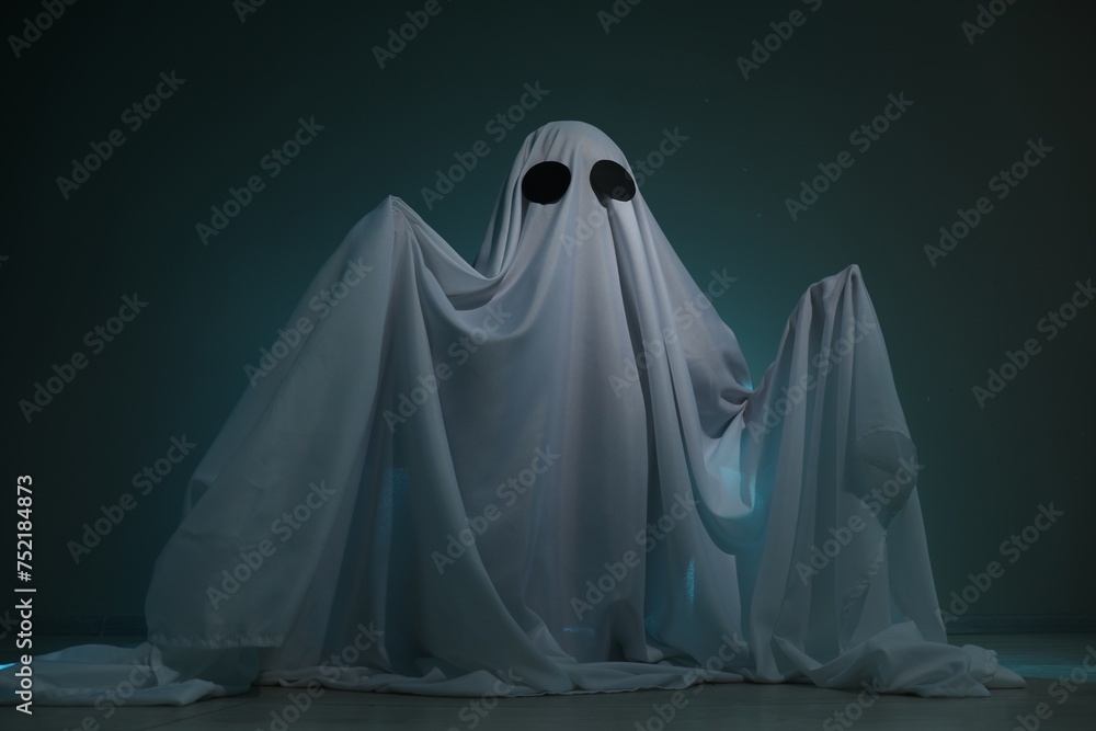Creepy ghost. Woman covered with sheet on dark teal background Creepy ghost. Woman covered with sheet on dark teal background