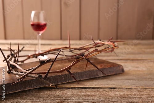 Crown of thorns and glass with wine on wooden table  selective focus