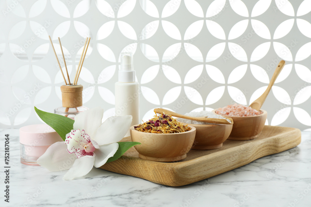 Beautiful composition with different spa products and orchid on white marble table Beautiful composition with different spa products and orchid on white marble table