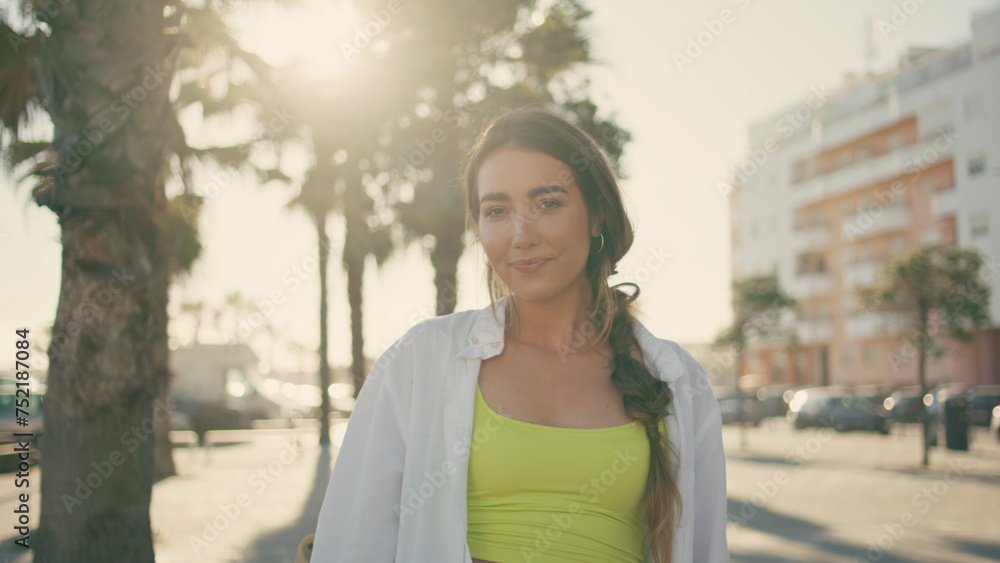 Smiling model posing camera at palm trees alley portrait. Woman relaxing at city Smiling model posing camera at palm trees alley portrait. Woman relaxing at city