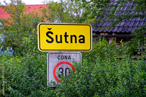 Close-up of yellow sign and speed limit 30 road sign at rural village of Sutna on a cloudy summer evening. Photo taken August 10th, 2023, Šutna, Kranj, Slovenia. photo