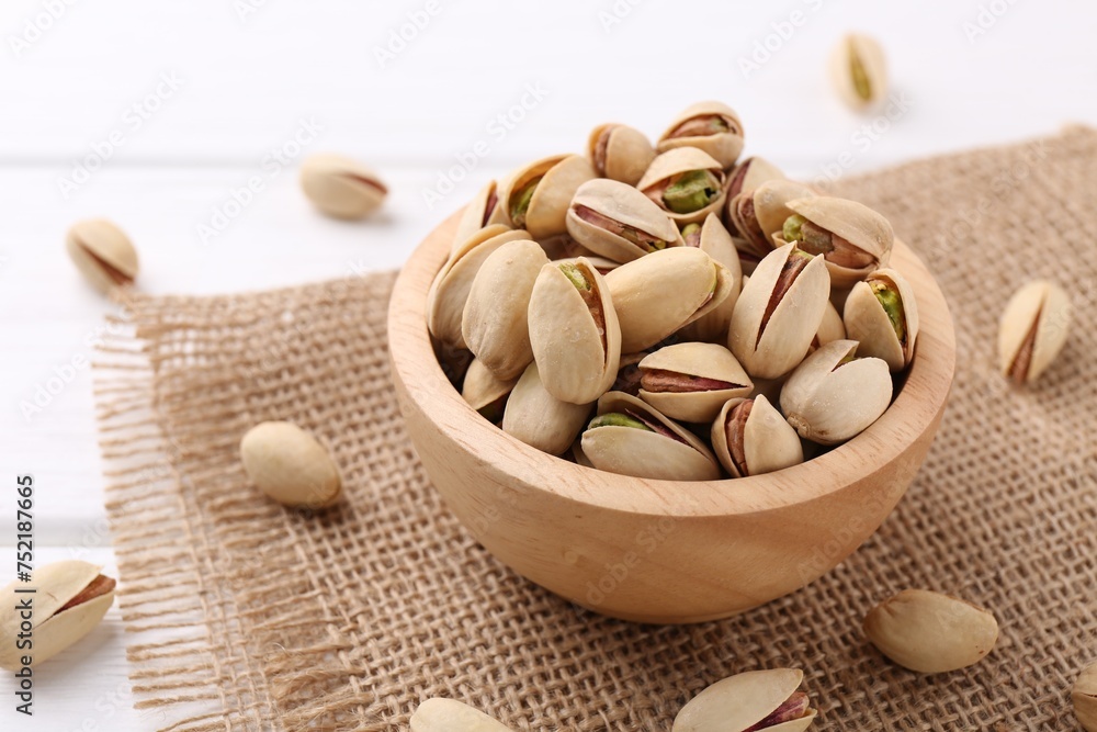 Tasty pistachios in bowl on white wooden table Tasty pistachios in bowl on white wooden table