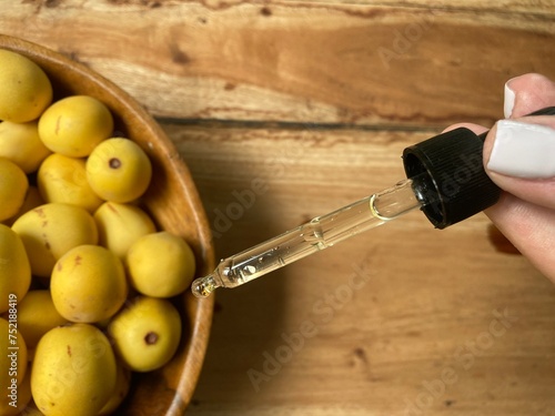 Marula fruit cosmetic oil in a dropper with marula fruit in soft focus photo