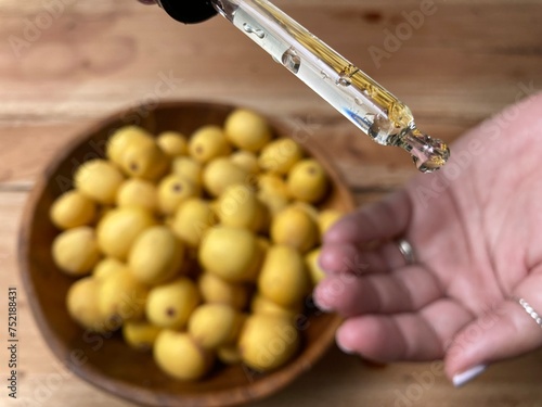 Marula fruit cosmetic oil in a dropper with marula fruit in soft focus