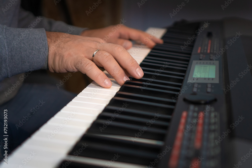 Close-up of male hands playing an electronic piano. Musical education at a music school. Private music lessons with a teacher. Close-up of male hands playing an electronic piano. Musical education at a music school. Private music lessons with a teacher.