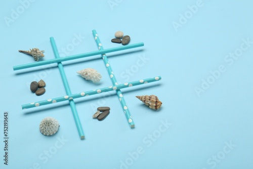 Tic tac toe game made with sea treasures on light blue background