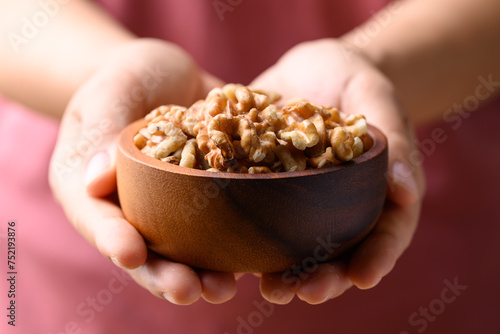 Organic raw walnuts in wooden bowl holding by hand, Food ingredient