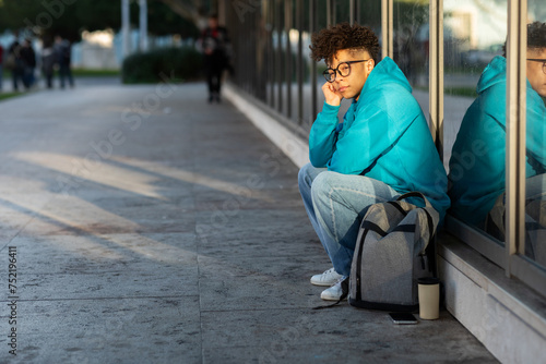Cuadro en lienzo Unhappy black student guy sitting with backpack outdoors at night