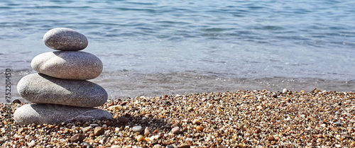 Spa stones balance on the sand of the beach.