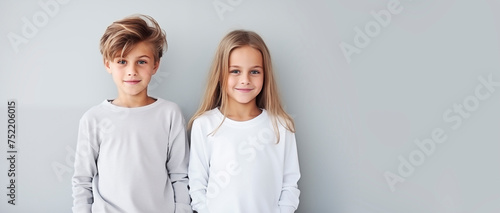 Brother and sister in light clothes, children standing next to each other and smiling, empty space for text, national siblings day, banner. Portrait of cute children on a light background photo