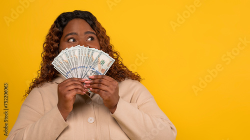 Amazed african american chubby lady cover her mouth with cash photo