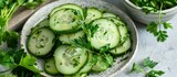 Neatly sliced cucumbers arranged in a bowl with parsley on the side.