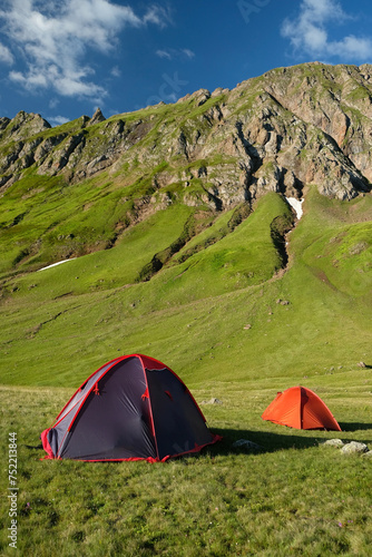 landscape with touristic tents in green big mountains and blue sky  nature background. trip  journey  hiking  adventure concept. summer season in Caucasus mountains  Karachay-Cherkess Republic. Arkhyz