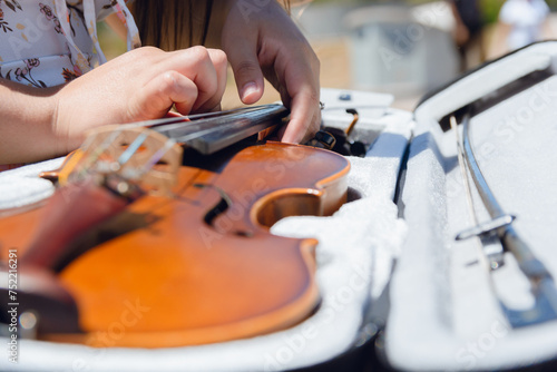closeup of young unrecognizable busker woman on street keeping violin in case
