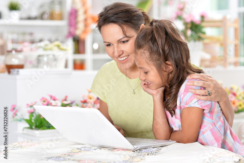 Portrait of happy mother and daughter using laptop