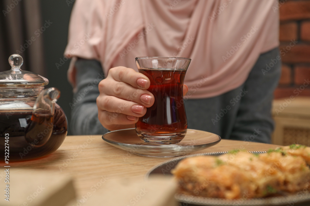 Woman with cup of delicious Turkish tea at wooden table, closeup Woman with cup of delicious Turkish tea at wooden table, closeup