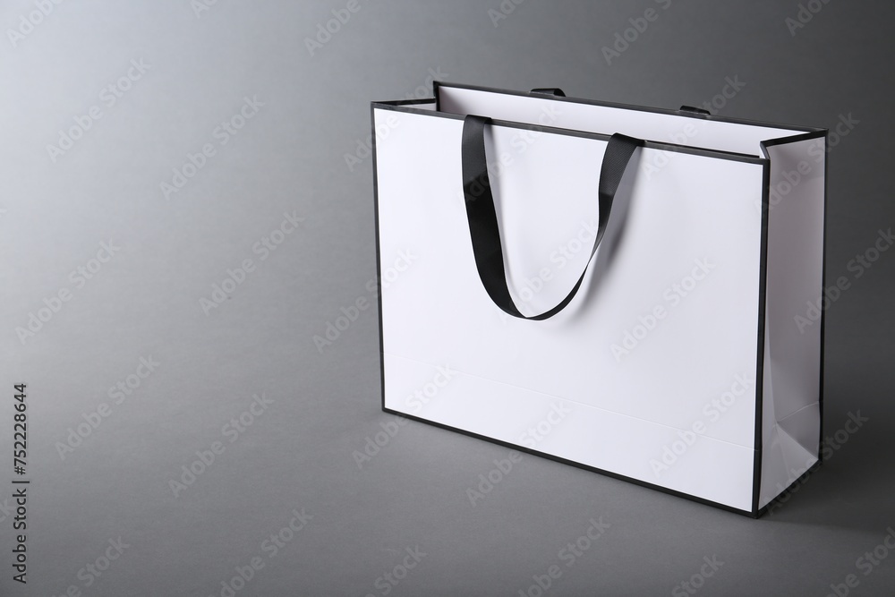 Fototapeta premium One paper bag on grey background, space for text. Mockup for design