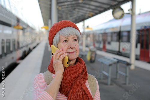 Senior woman talking on the phone at train station platform 