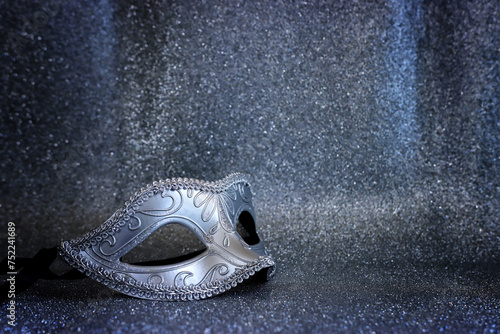 Photo of elegant Venetian mask over glitter silver background