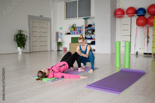  Rehabilitation after injuries. Physiotherapist shows correct execution of stretching woman with problem with her back and ligaments.Concept of getting rid of back pain, restoring health of the spine.