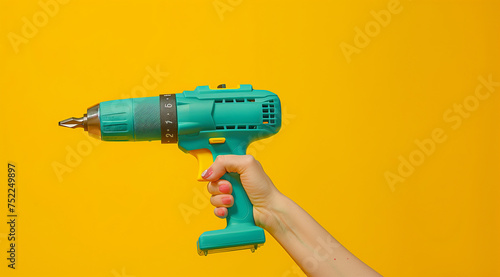 Hand Holding Electric Drill on Yellow Background