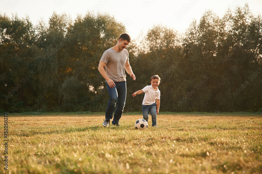 Conception of soccer game. Father and little son are playing and having fun outdoors Conception of soccer game. Father and little son are playing and having fun outdoors